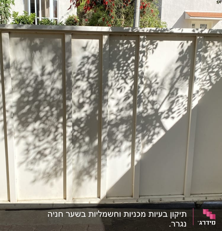 שער חשמלי לבן עם מנוע קטן בתחתית